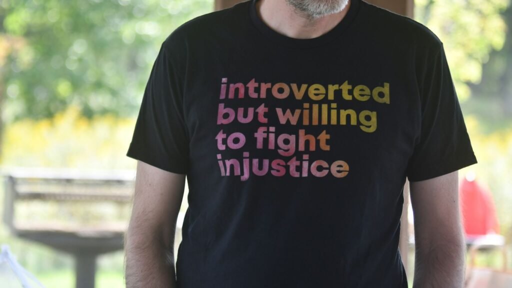 Man wears t-shirt with "introverted but willing to fight injustice".
