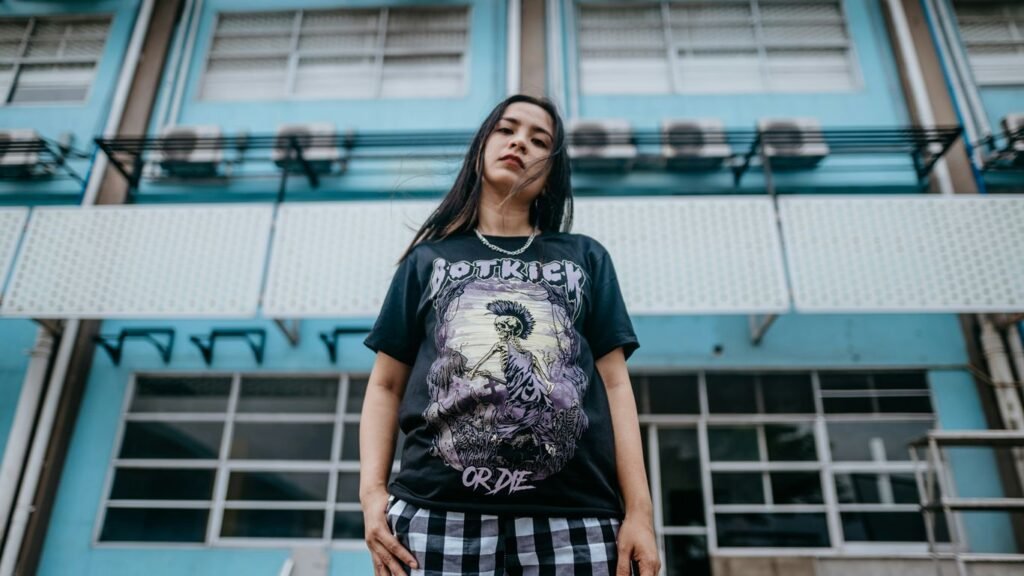 woman in black crew neck t-shirt and black and white plaid skirt standing on gray